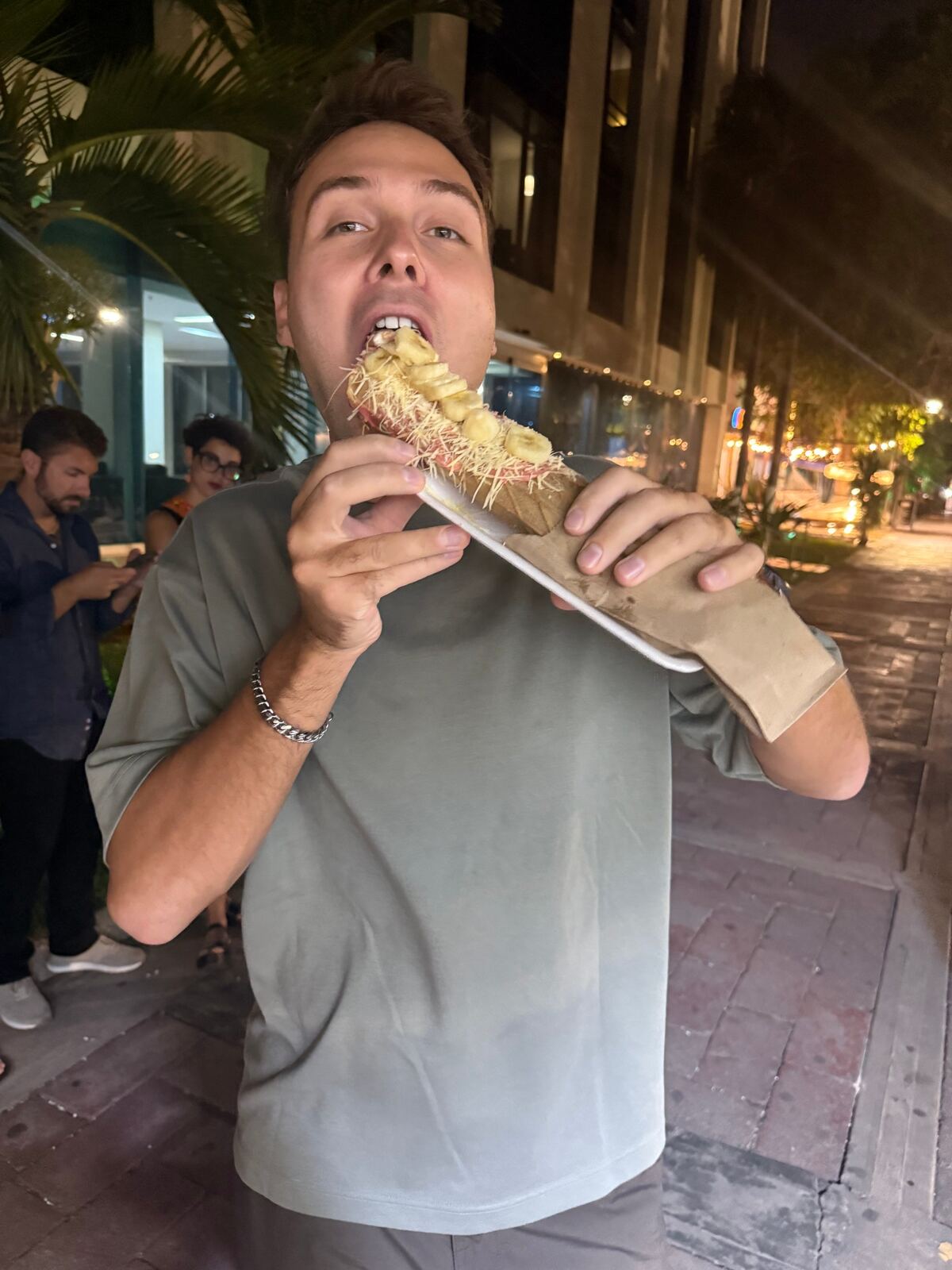 Elijah taking a big bite of street food at night